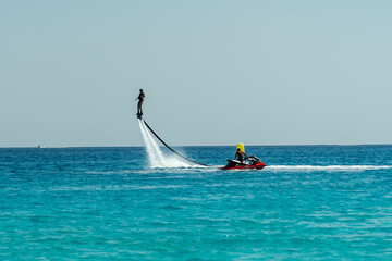 Man flyboarding above the clear sea. Water sports adventure