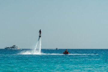 Man flyboarding above the clear sea. Water sports adventure