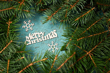 New Year composition from Wooden Christmas tree and snowflakes on a blue paper background surrounded by fir branches