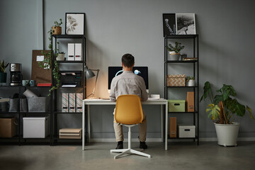 Wide angle back view at man using computer at home office with modern tech interior, copy space