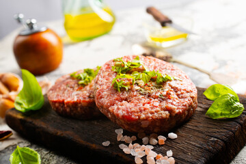 Raw cutlet of minced meat on a wooden cutting board.