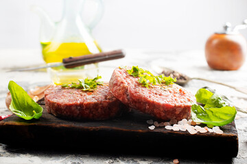 Raw cutlet of minced meat on a wooden cutting board.