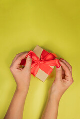 girl unties bow gift box on yellow background