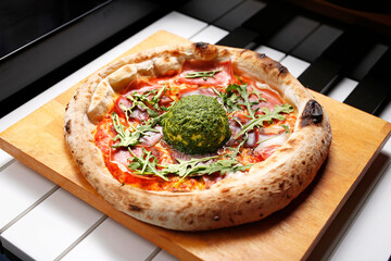Pizza with Parma ham, arugula, and burrata cheese with green pesto.
A tasty dish.Culinary photography. Suggestion to serve the dish.
