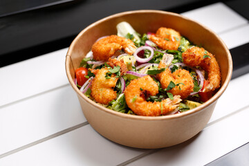Fried prawns on a green salad. Takeaway, diet box.
Appetizing ready-to-go dish served in a disposable box. Culinary photography. Food background.