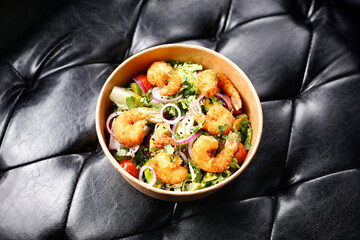 Fried prawns on a green salad. Takeaway, diet box.
Appetizing ready-to-go dish served in a disposable box. Culinary photography. Food background.