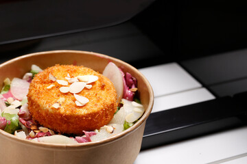 Fried camembert cheese on a green salad. Takeaway, diet box.
Appetizing ready-to-go dish served in a disposable box. Culinary photography. Food background.