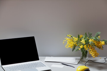 Mimosa bouquet and laptop on desktop