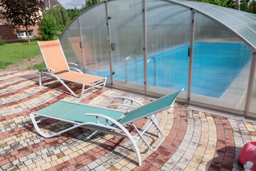 Modern chaise longue stands in front of outdoor indoor pool