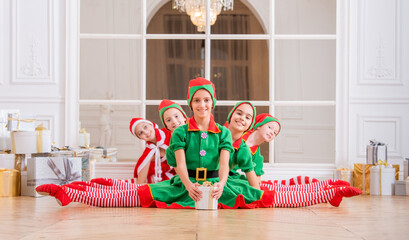 Children dressed in costumes of Christmas elves sitting in twine one after another in front of the...