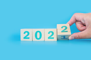 Hand flip a cube wooden block with the text 2022, start and trend, calendar and time, goal of...