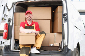 Man courier holding a parcel while sitting in the truck