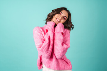 Cozy portrait of a young woman in a pink knitted sweater and with bright makeup on a turquoise background