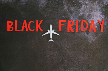 Black Friday concept. Inscription "black friday", toy airplane, small globe, writing board with word "Sale" on black background. Copy space, top view, flat lay. Creative holiday, travelling concept