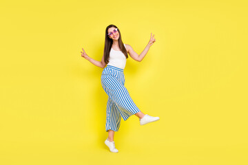 Fototapeta na wymiar Full length body size view of charming cheerful girl dancing showing v-sign having fun isolated over bright yellow color background