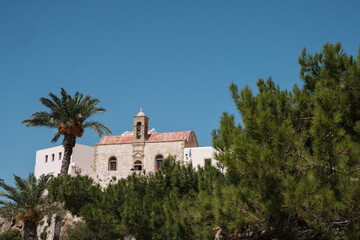 Fototapeta na wymiar View on Chrisoskalitissa monastery through the trees and behind clear sky