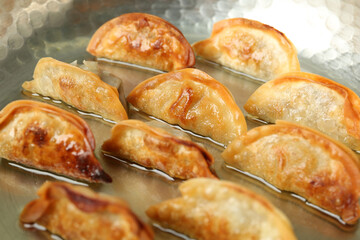 Cooking gyoza on frying pan with hot oil, closeup