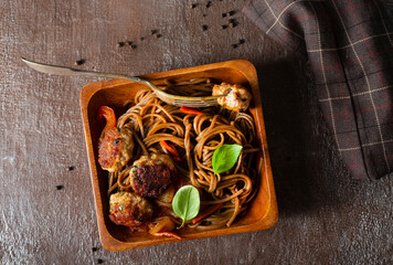 Plate soba with fried cutlets and sauce on a table.