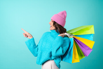 Cozy portrait of a young woman in a knitted blue sweater and a pink hat with bright makeup holds shopping bags