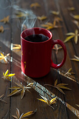 a mug of coffee on the table and autumn leaves