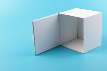 Opened white paper cube box on a blue background.