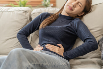 Obraz premium Flatulence asian young woman, girl hand in stomach ache, suffer from food poisoning, abdominal pain and colon problem, gastritis or diarrhoea. Patient belly, abdomen or inflammation, concept.