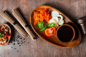 raw soba and fresh vegetables . raw vegetables and sauce on plate