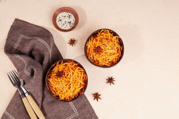 Asian pickled spicy salad of grated carrots with pepper, sesame and garlic. Korean-style carrots in bowls . 