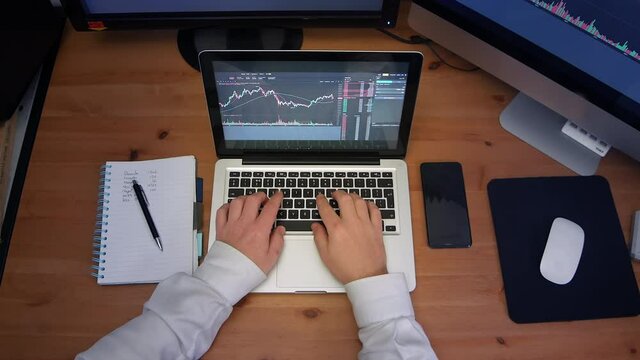 Timelapse Of Business Man Working Hard At Desk Taking Notes On A Busy Business Day. A Birdseye View Of Laptop, Notepad, Phone And Desktop Computers.