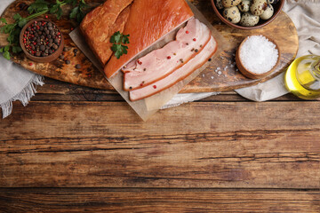 Flat lay composition with delicious smoked bacon on wooden table, space for text