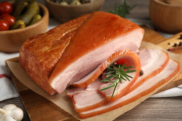 Delicious smoked bacon with rosemary on wooden table, closeup