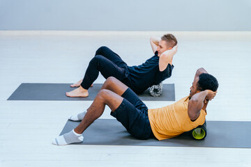 Male pilates trainer nad african american man, individual training participant, do perform...