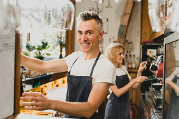 Confident smiling middle-aged small business owners barista bartenders waiters in blue aprons...