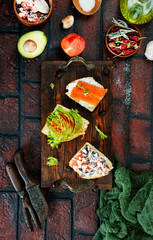healthy sandwiches with smoked salmon avocado cucumber cream cheese on rye bread on dark background