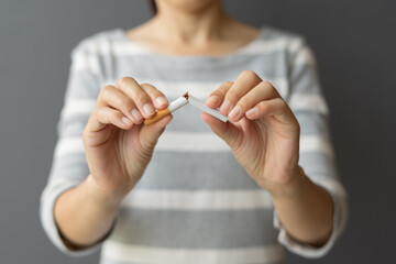 Portrait young woman holding broken cigarette in hands. Happy female quitting refusing smoking cigarettes. Quit bad habit, Stop smoking cigarettes, health care concept. No smoking campaign.