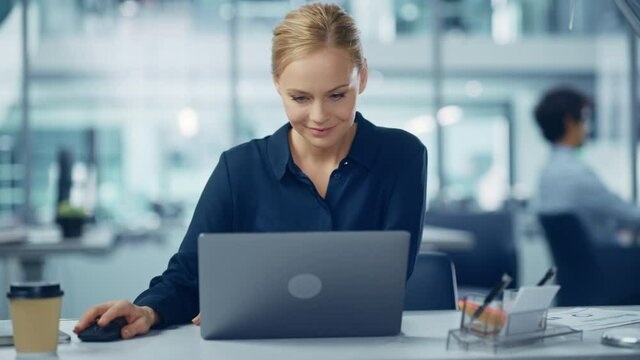 Modern Office: Portrait of Successful Young Adult Businesswoman Working on a Laptop at his Desk. Smiling Confident Digital Entrepreneur. Beautiful Professional Specialist. Medium Front View Arc Shot