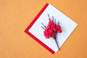 和紙の上の梅の花束のデザイン(オレンジ色の和紙）