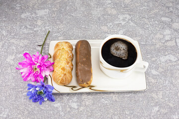 White cup of black coffee, served on white saucer with macaroons biscuits, spoon and magnolia...