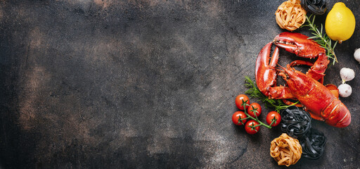 Red prepared lobster with pasta and vegetables on dark background. Top view. Long banner with copy...