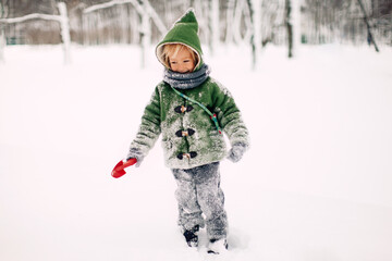 Fototapeta na wymiar Joyful Little Girl in Green Hooded Winter Gnome Coat Standing in Snow