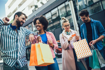 Group of friends walking along street with shopping bags and having fun.