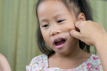 Asian mother and child girl playing pinch cheeks, touch nose funny face.