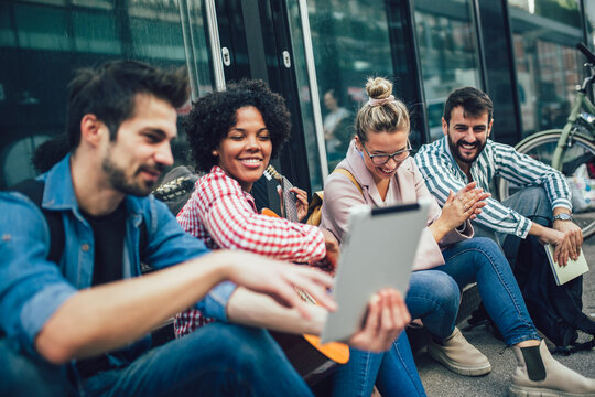 Group Of Young Friends Hangout In City.They Are Sitting,singing And Playing Guitar.