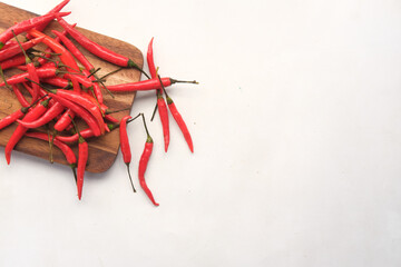 top view of red chili on a chopping board on white 