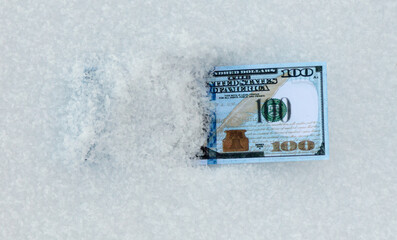 One Hundred Dollars lie in the snow.