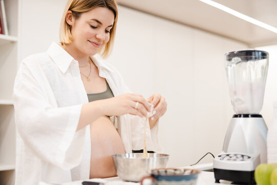 White pregnant woman smiling while cooking with eggs in kitchen