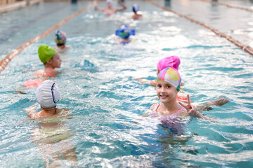 Little girl swimming in swimming pool with friends