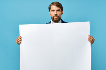 Cheerful man white banner in hand blank sheet presentation blue background