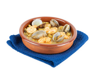 Fabas verdinas with prawns and clams in an earthenware casserole on a white background. Copy space.