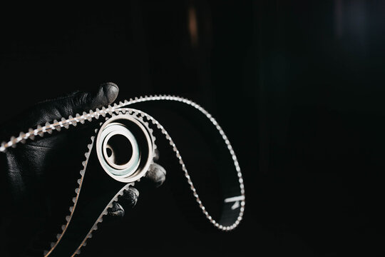 automotive timing belt on a black background. Replacement concept for idler pulleys and engine belts.